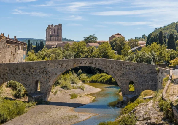 Pont médiéval en Pierre avec l'abbaye de Lagrasse en arrière plan. Paysage ensoleillé.